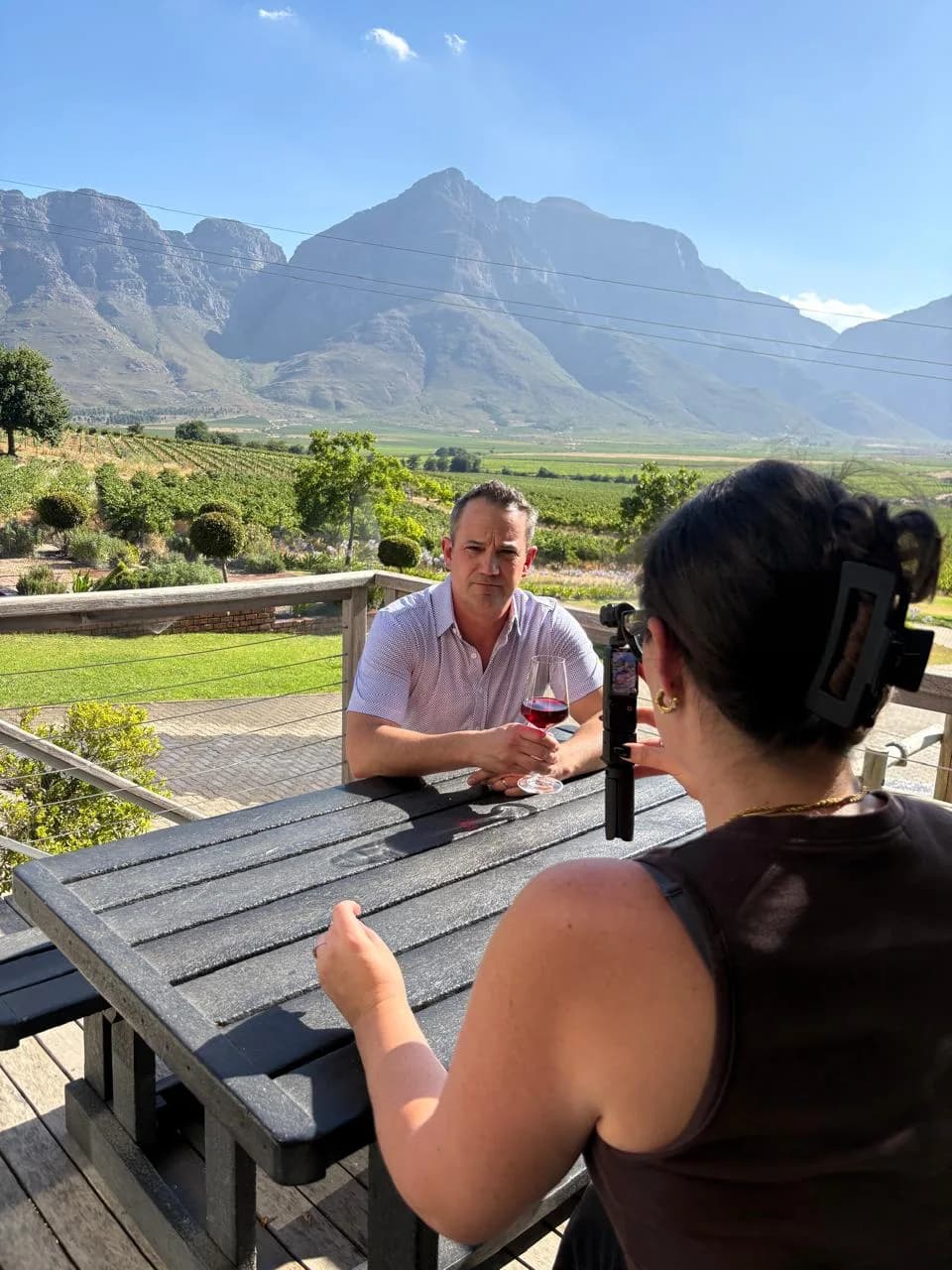 Meeting a producer at an estate table, winelands mountains behind