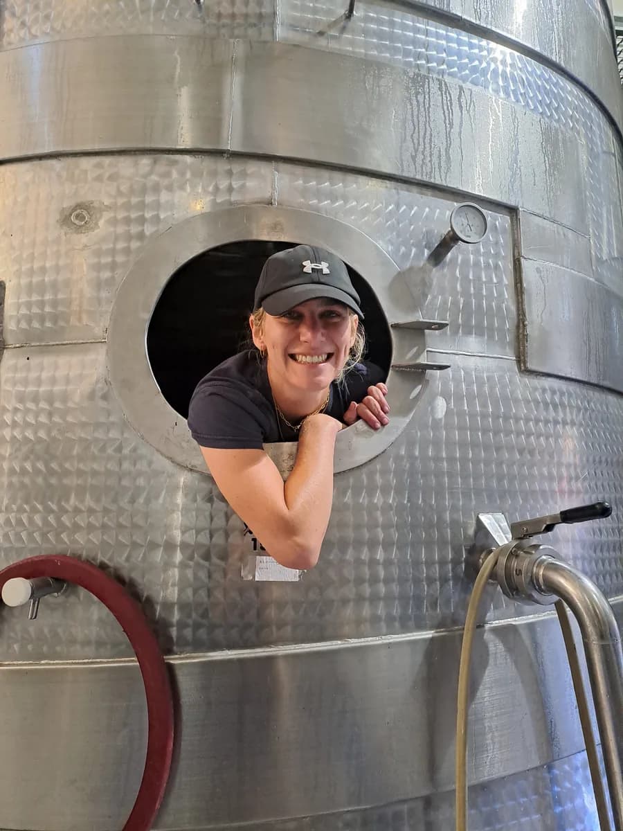 A cellar team member smiling from inside a stainless steel tank