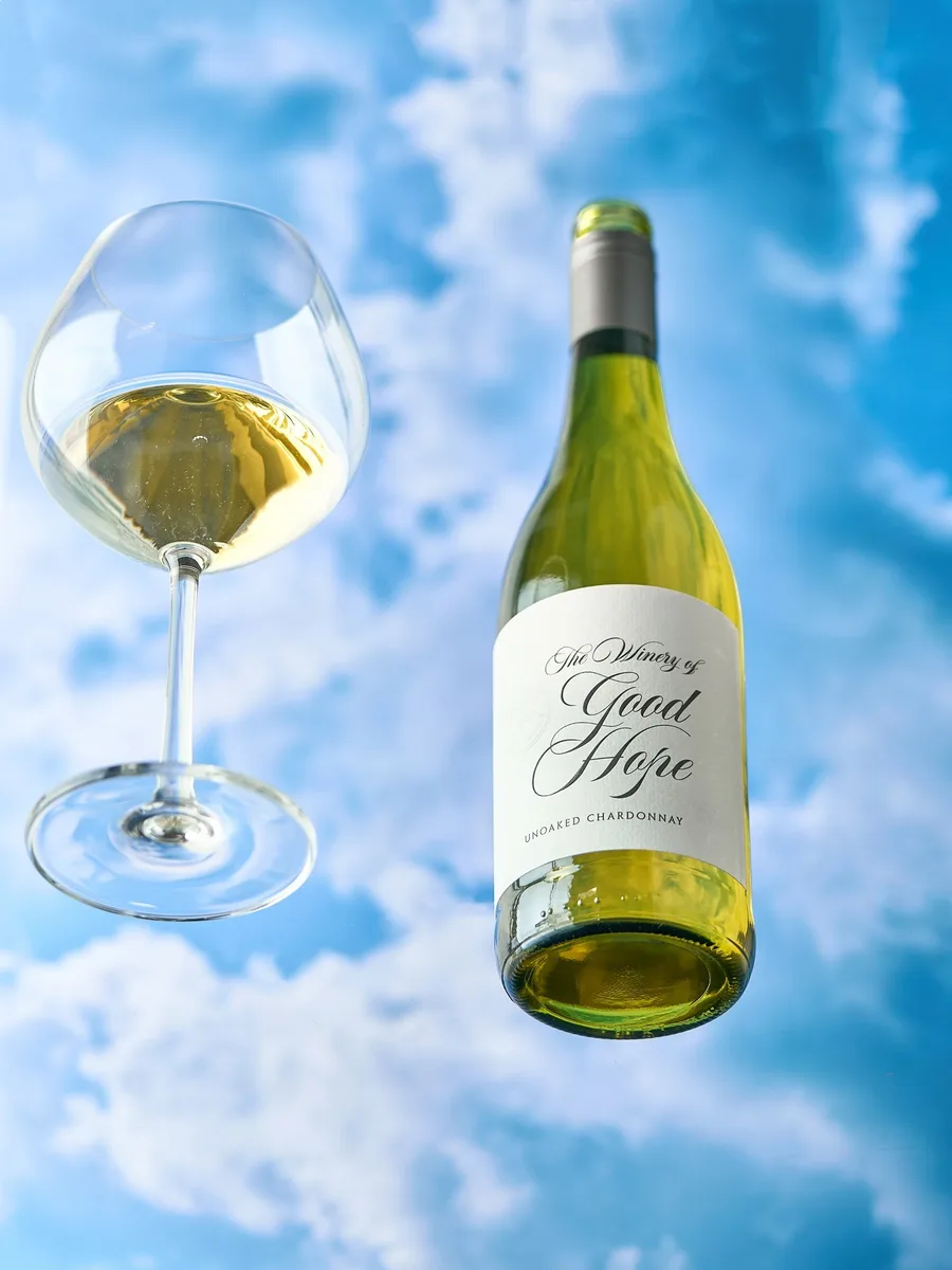 A bottle and glass of Unoaked Chardonnay against a summer sky