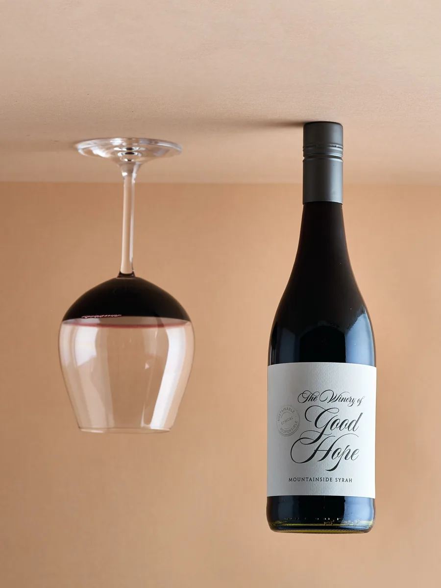 A bottle of Mountainside Syrah with a glass hung above it