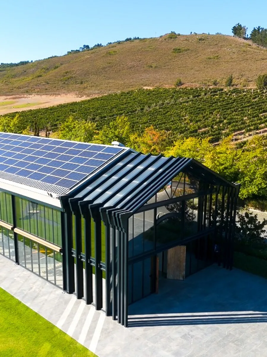 A modern winery building with a solar roof overlooking the vineyard